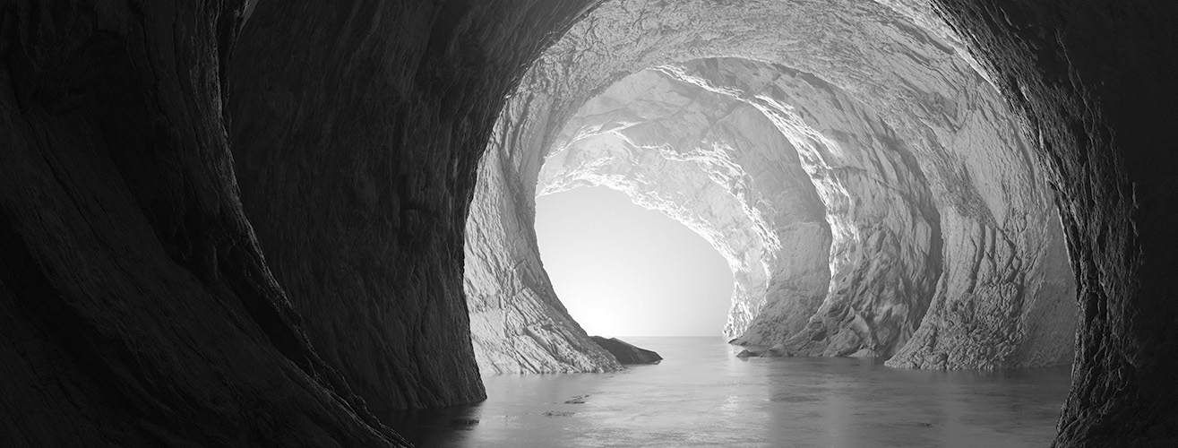 In den Fels gehauener Tunnel, von dessem hinteren Ende ein Licht strahlt